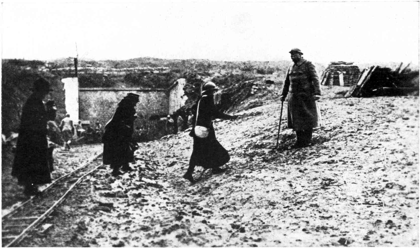 THE COMMANDING OFFICER OF THE CITADEL OF VERDUN. NEXT, ON LEFT, MISS FRAZER, IN     HELMET, CARRYING GAS MASK. THE TUNNEL-ENTRANCE TO THE FORTRESS IS IN THE BACKGROUND.
